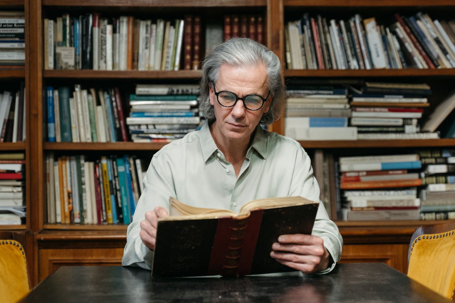 A man reading a book among library shelves